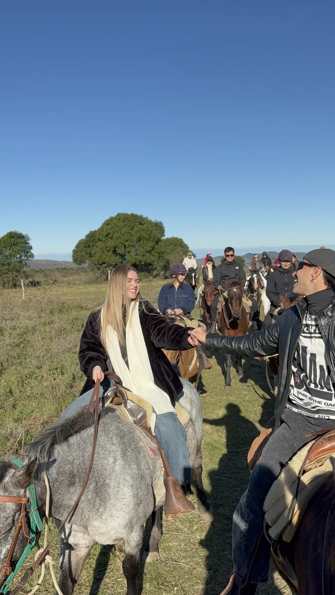 Dos amigos se saludan a caballo durante la cabalgata